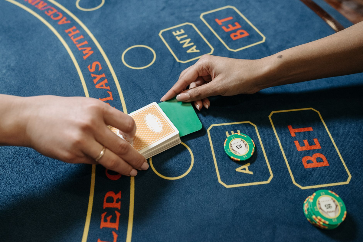 Croupier hands mid-deal in cuffed uniform sleeves under a warm spotlight